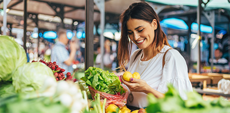 Woman shop for healthy foods to avoid triggers at a farmers market. 