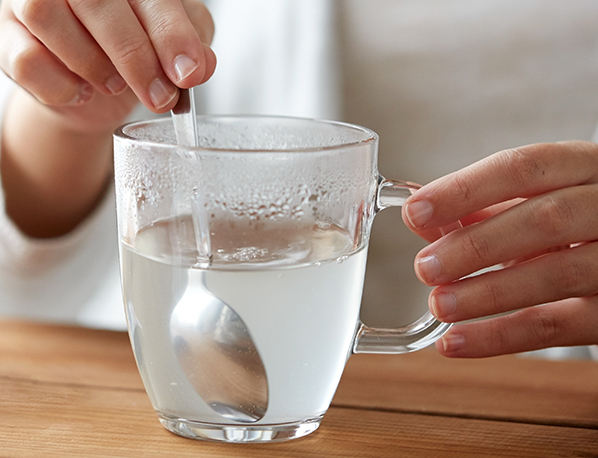 A woman stirs fiber or laxative into a cup of water.