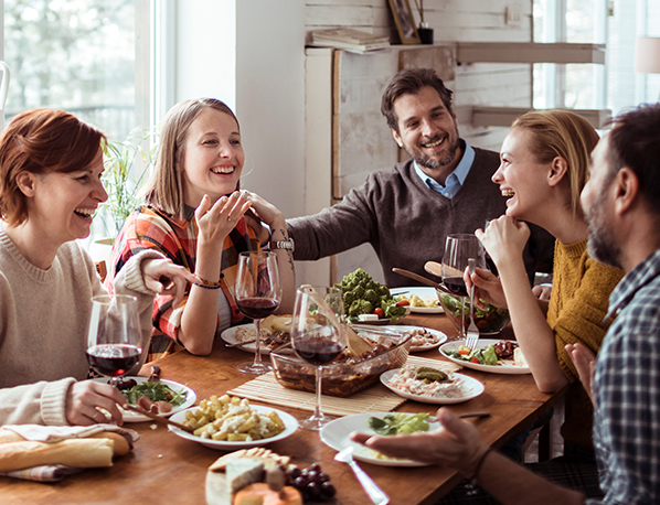 A group gathers around the table to enjoy a Low FODMAP holiday meal together.