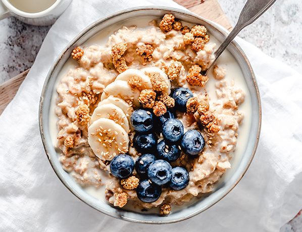 A delicious and healthy bowl of cereal topped with banana and blueberry. 